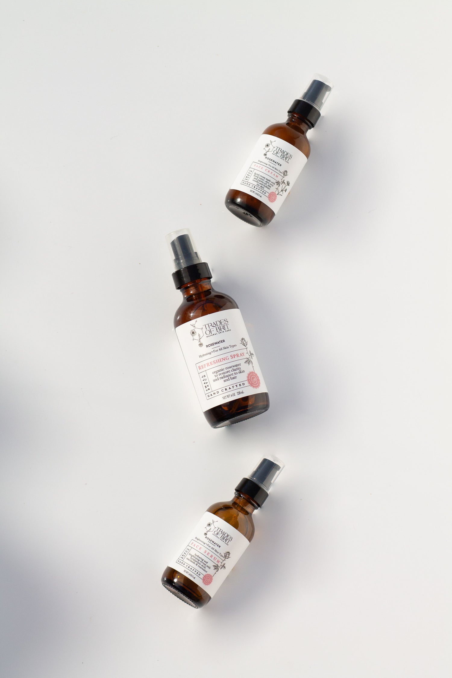 Three  Trades of Brit face care amber glass bottles with labels on a light gray background
